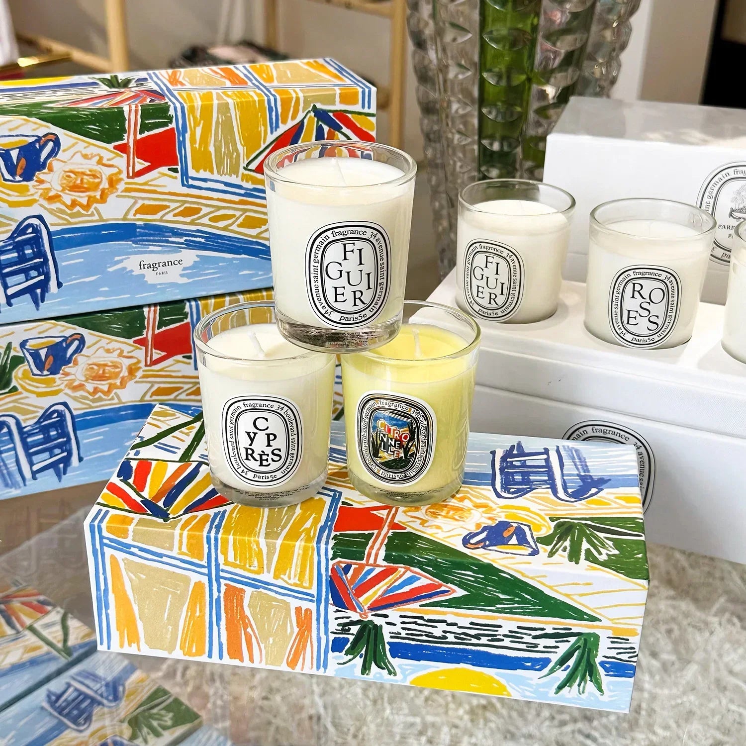 five decorative candles  in a white glass jar with the candles box on the table 