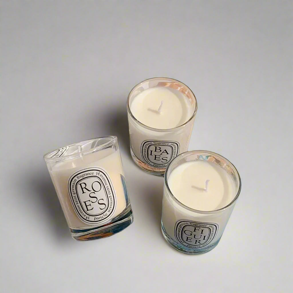 three decorative candles (figuier, roses and baies) in a white glass jar on white background