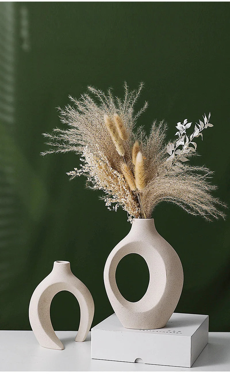 White ceramic vase featuring floral relief details displayed on a dark green background and white surface.