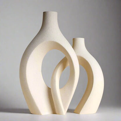 Set of three ceramic vases in neutral tones with distinct geometric shapes displayed against an gray background